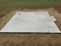 Płyta fundamentowa koszt. Betonowa płyta na budowie, otoczona ziemią i elementami instalacji.