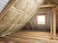 Izolacja poddasza wełną mineralną. Czy 15 cm wełny wystarczy na poddaszu? Widok na drewnianą konstrukcję dachu i okno dachowe.