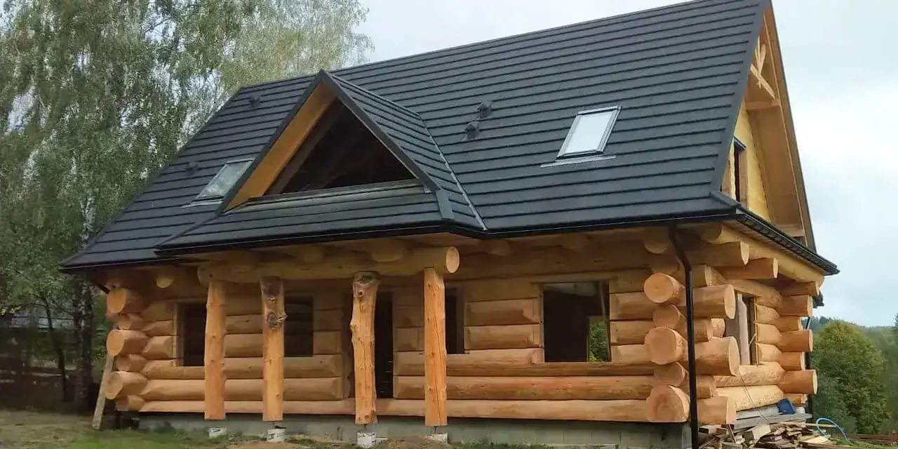 Piękny dom z bali, który budzi pytanie: czy dom z bali trzeba ocieplać? Grube bale zapewniają naturalną izolację.