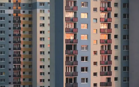 Widok na fasadę wielopiętrowych bloków mieszkalnych z balkonami i oknami.