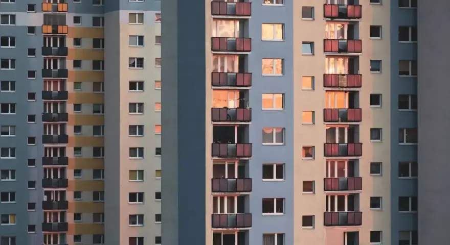 Widok na fasadę wielopiętrowych bloków mieszkalnych z balkonami i oknami.