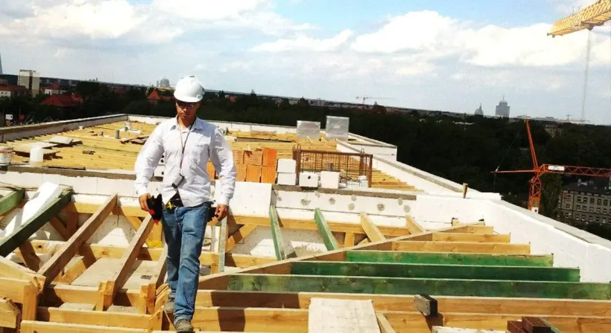 Budowlaniec w kasku na dachu w trakcie odbioru mieszkania.
