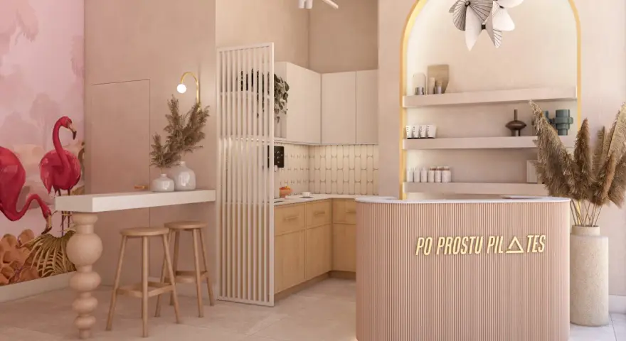 Nowoczesne wnętrze studia pilates z różowymi flamingami na ścianie i ladą recepcyjną.